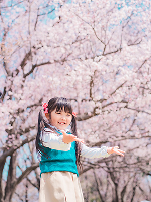 桜を背景に女の子が笑顔の写真